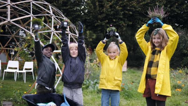 Vier Kinder im Garten mit Pflanzen in der Hand